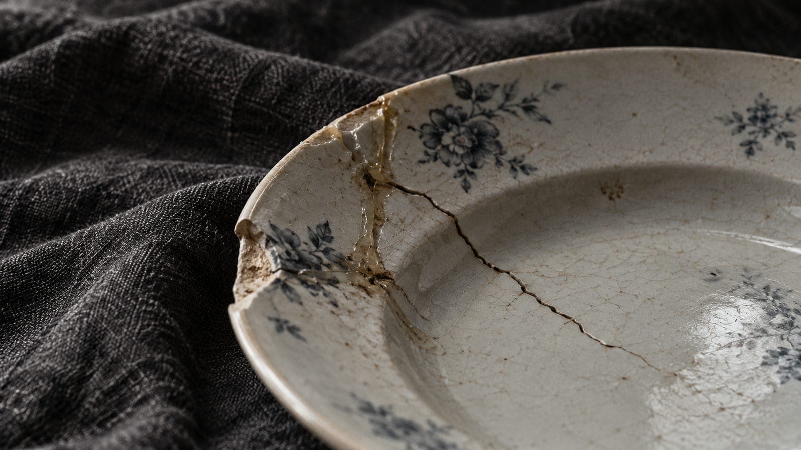 A new crack runs beside an old repair in a chipped porcelain plate.